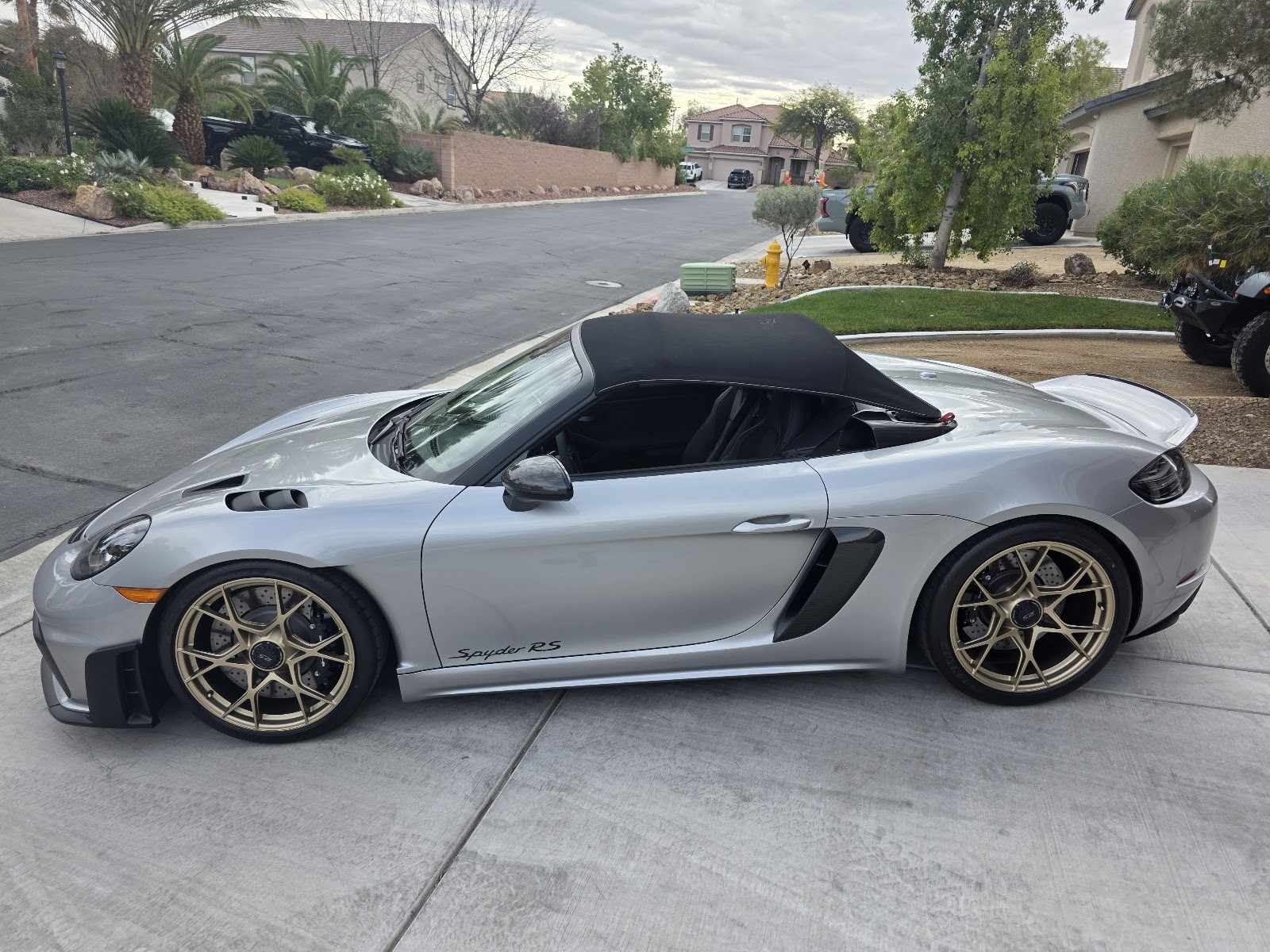 Detailed silver Porsche 718 Spyder RS with bronze wheels in a driveway
