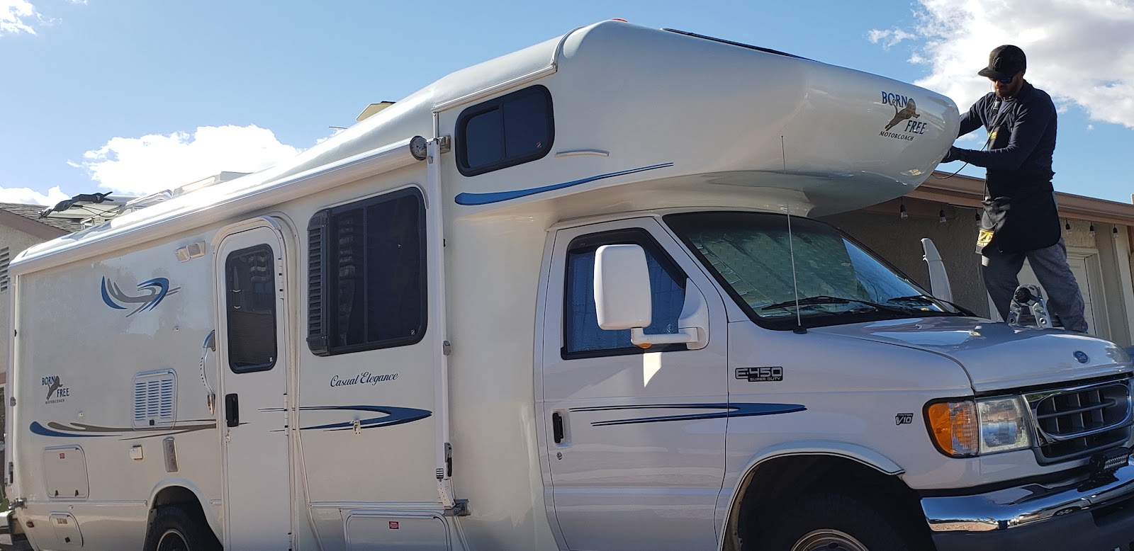 Detailer working on top of a Born Free Class C motorhome RV